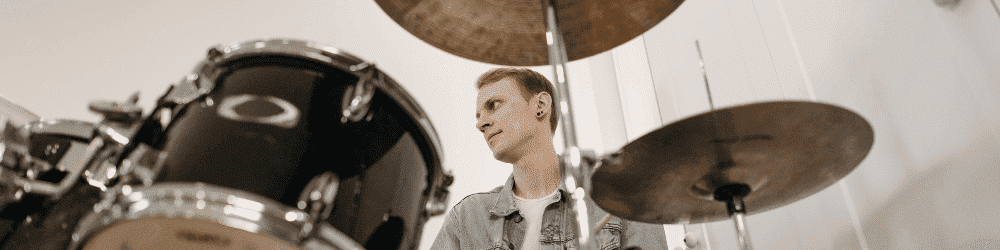 A drummer deeply focused, playing on his drum set, showcasing essential drumming techniques in action.