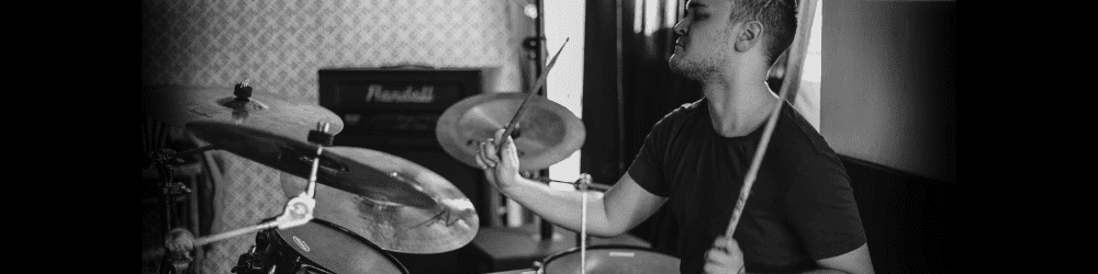 A drummer playing in his home studio, fully immersed in his drum set.