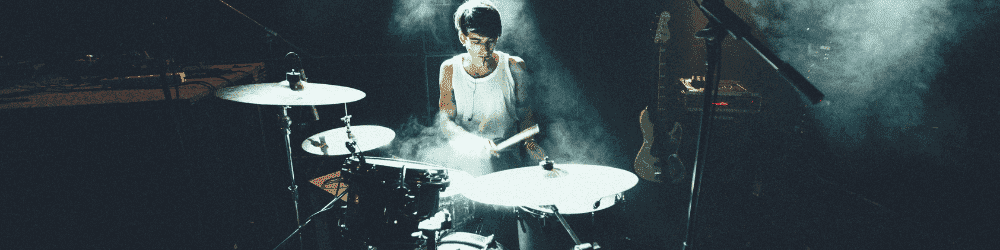 Talented drummer playing on a drum set on stage, showcasing his drumming skills.