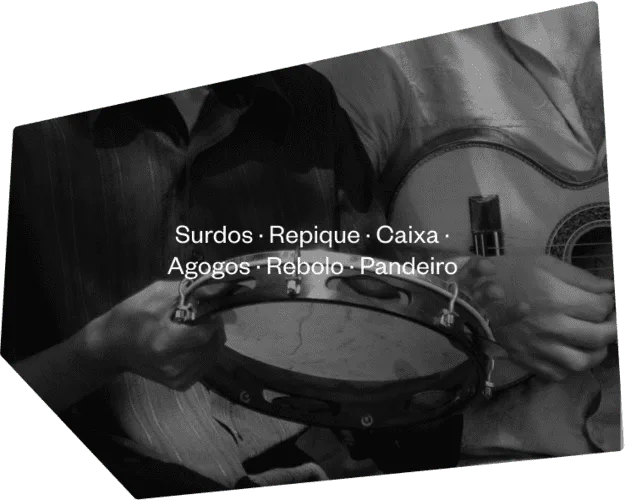 Musician playing surdos, repique, caixa, agogôs, rebolo, and pandeiro on stage.