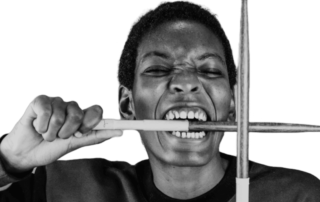 Excited female drummer showing off drumsticks, ready to play and learn with UpBeat Studio apps: Drum Coach and Drum Notes.