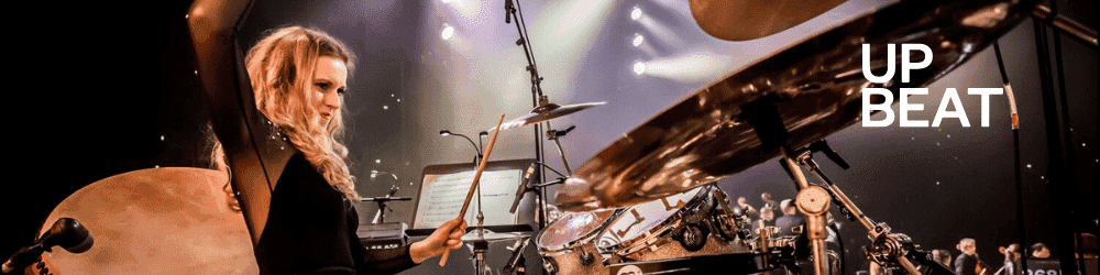 Lucy Landymore performing on her drum set during a live stage performance.